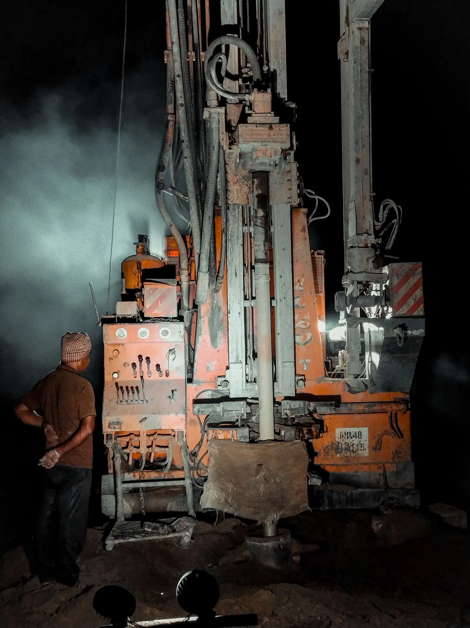 Water drilling rig running after dark with the operator at the controls